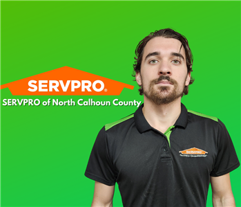 man with facial hair looking at camera on a green background with orange SERVPRO logo behind him
