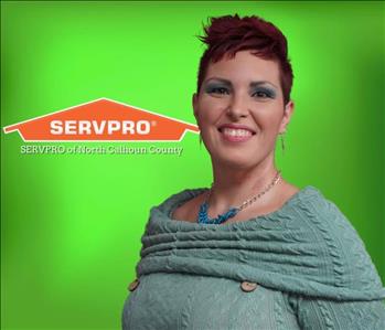 Red haired girl in black shirt against green background Servpro sign