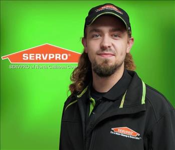 White male brown hair in black shirt against green background SERVPRO sign