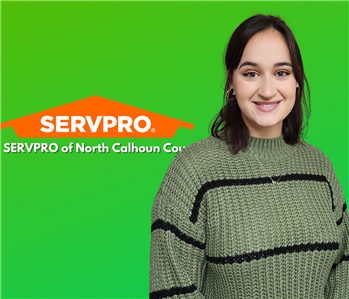 woman smiling on green background with SERVPRO logo behind her