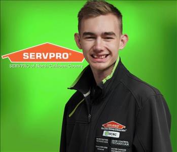 White male brown hair in black shirt against green background Servpro sign